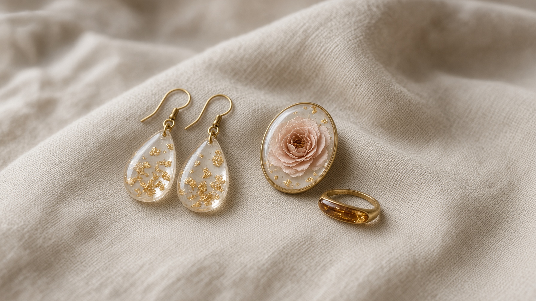 Resin earrings, a rose pendant and an amber ring arranged on linen