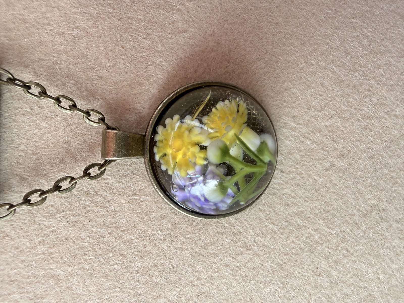 Round resin pendant with yellow and lilac flowers on an antique-brass chain
